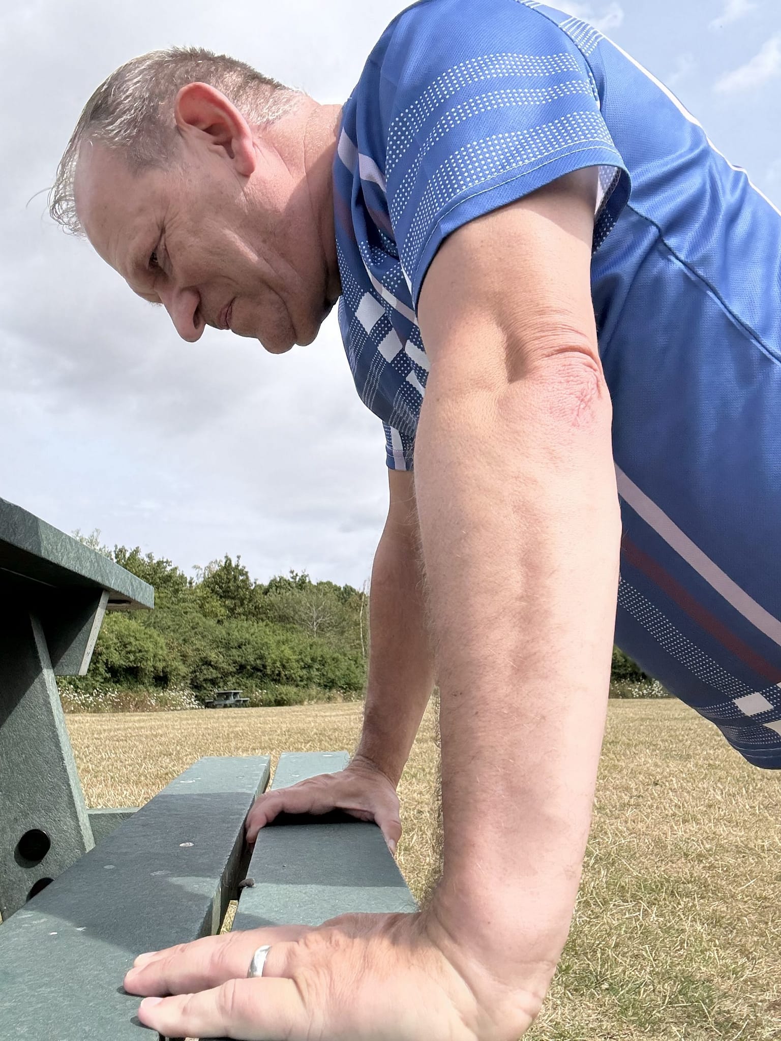 Strength training after 60 - Outdoor beginners push up on a sturdy park bench.